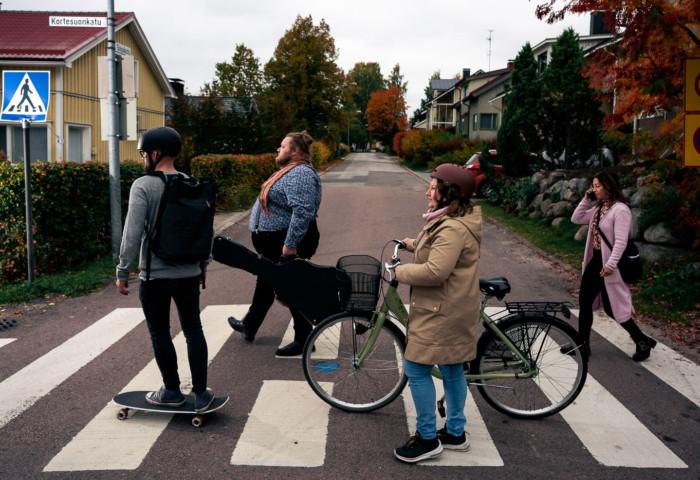 Ihmisiä ylittää suojatietä kävellen, skeitaten ja pyörää taluttaen.